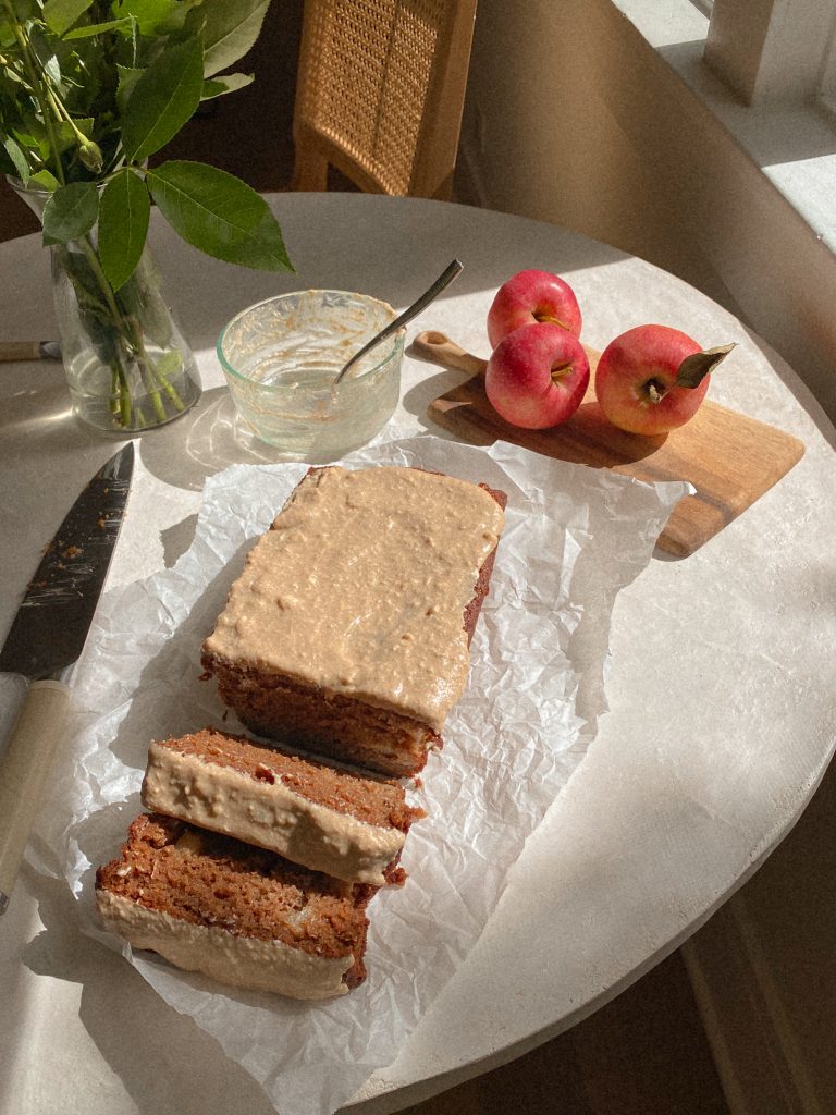 sliced apple bread on parchment paper on a table with apples on wood cutting board