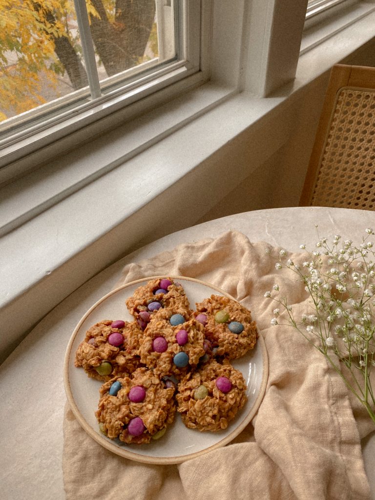 monster cookies on a white plate on a dish towel and white flowers