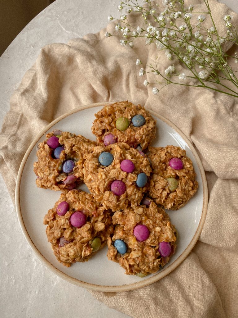 monster cookies on a white plate on a dish towel and white flowers