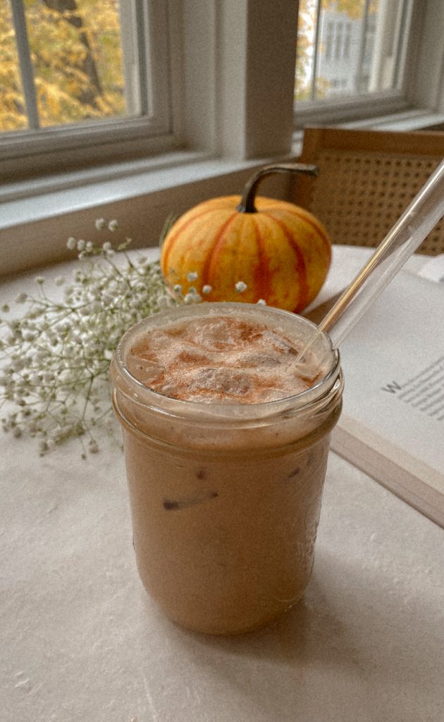 pumpkin cold brew in a jar with a glass straw with flowers and a pumpkin