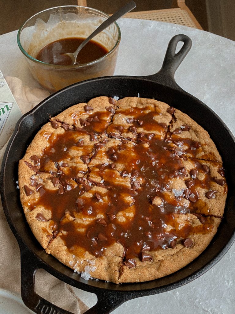 chocolate chip cookie skillet in a cast iron pan with caramel sauce  and flakey salt