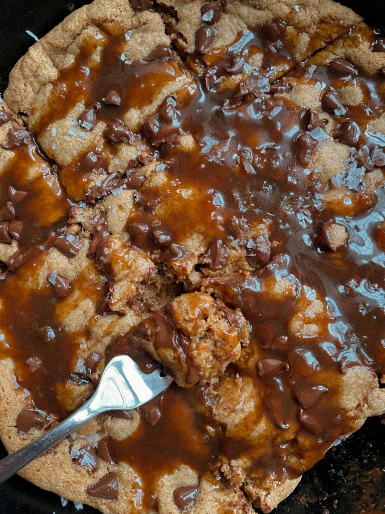 chocolate chip cookie skillet in a cast iron pan with caramel sauce 