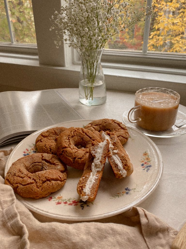 pumpkin bagels on a floral plate with a cup of tea and vase of white flowers