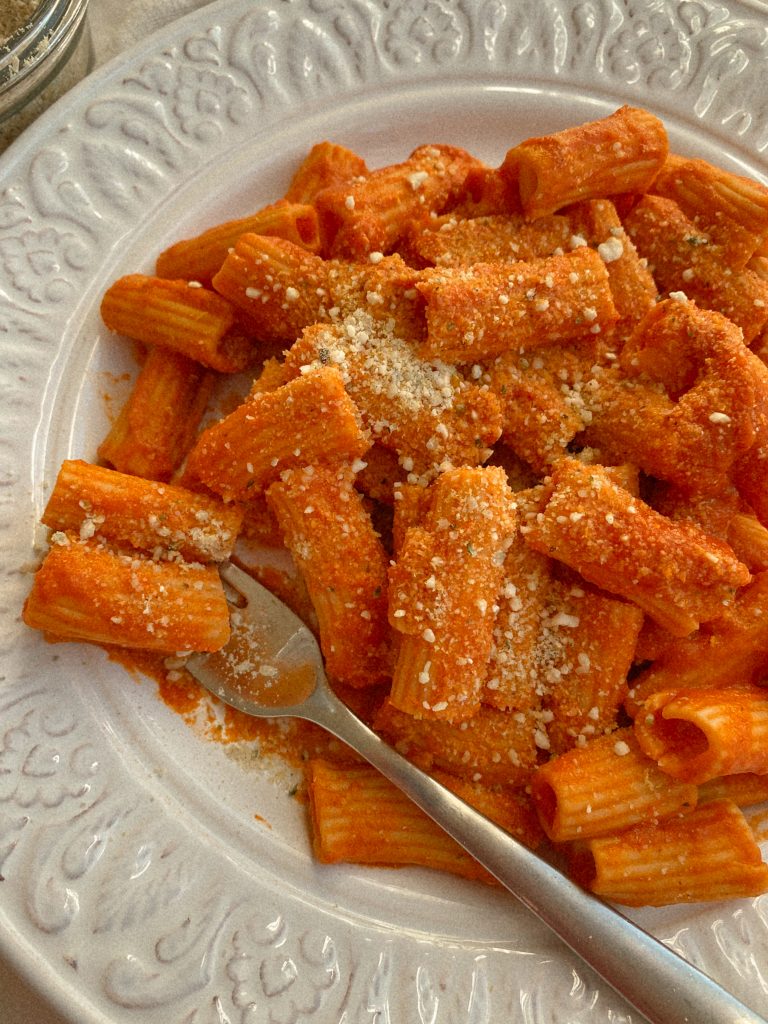 tomato sauce rigatoni pasta on a white plate with a fork