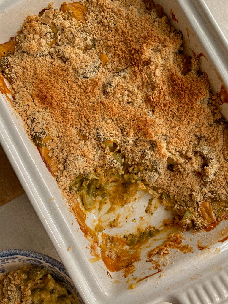 cheesy broccoli with cracker topping in white casserole dish 