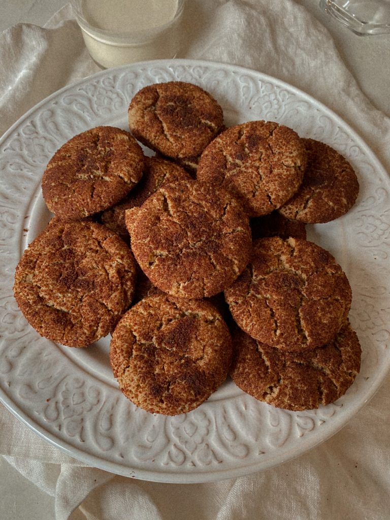 snickerdoodle cookies on a white plate with a glass of milk