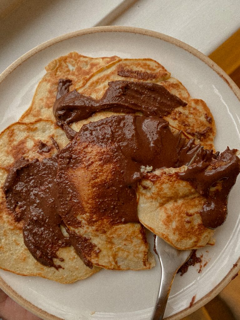 pancakes on a white plate with chocolate peanut butter on top and a fork