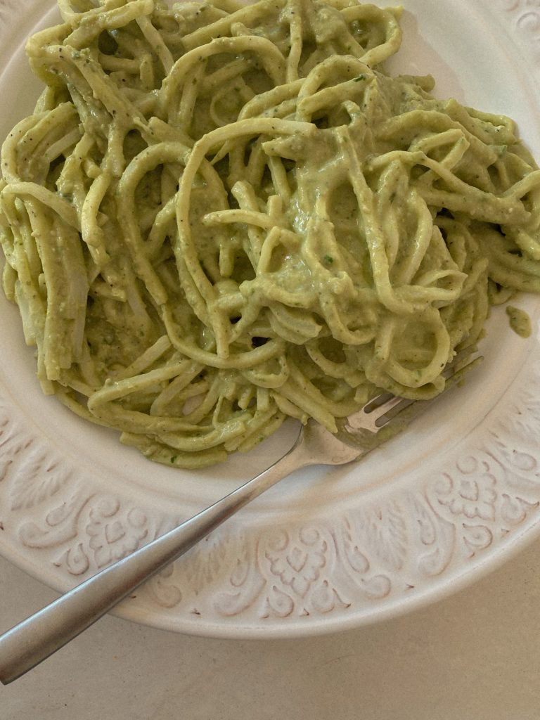 pesto cream sauce pasta with a fork on a white plate