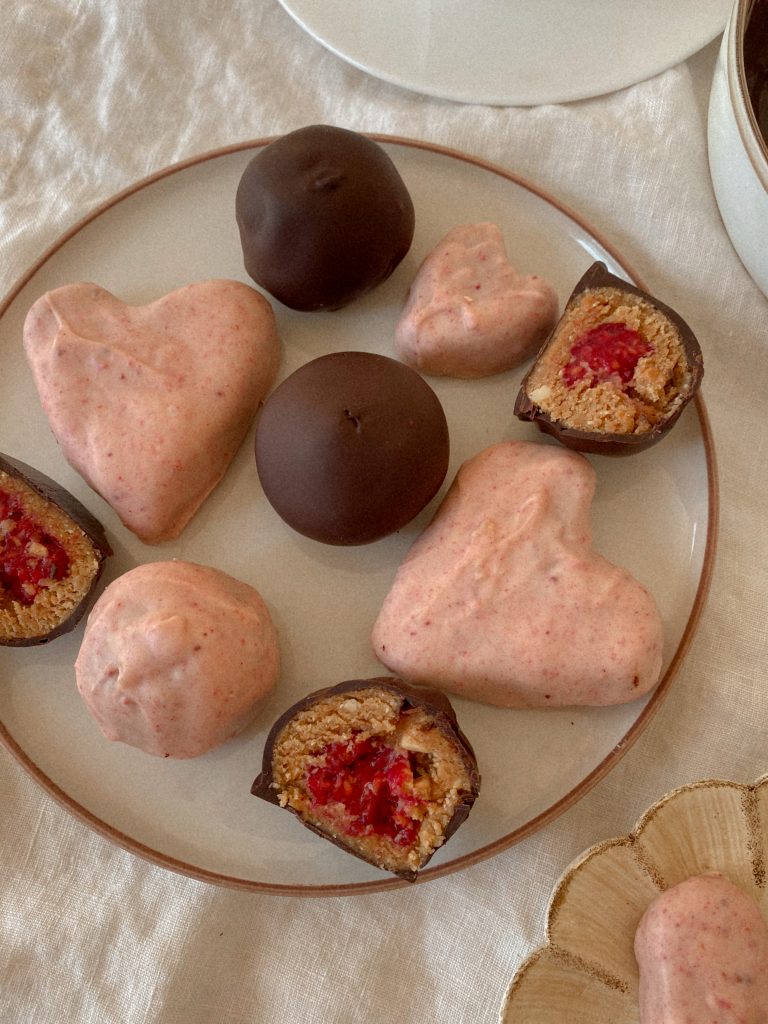 peanut butter heart shaped truffles dipped in pink white chocolate and raspberry stuffed truffles dipped in dark chocolate on a plate