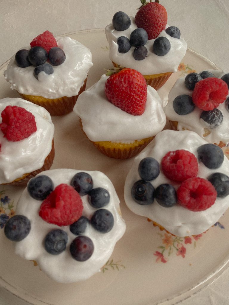 cupcakes with cool whip frosting and berries on top on a white plate