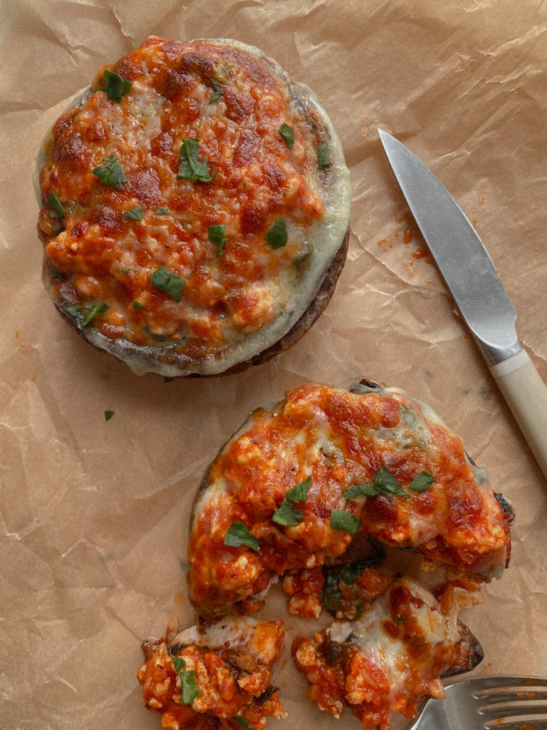 two portobello pizzas on brown parchment paper with a knife and fork