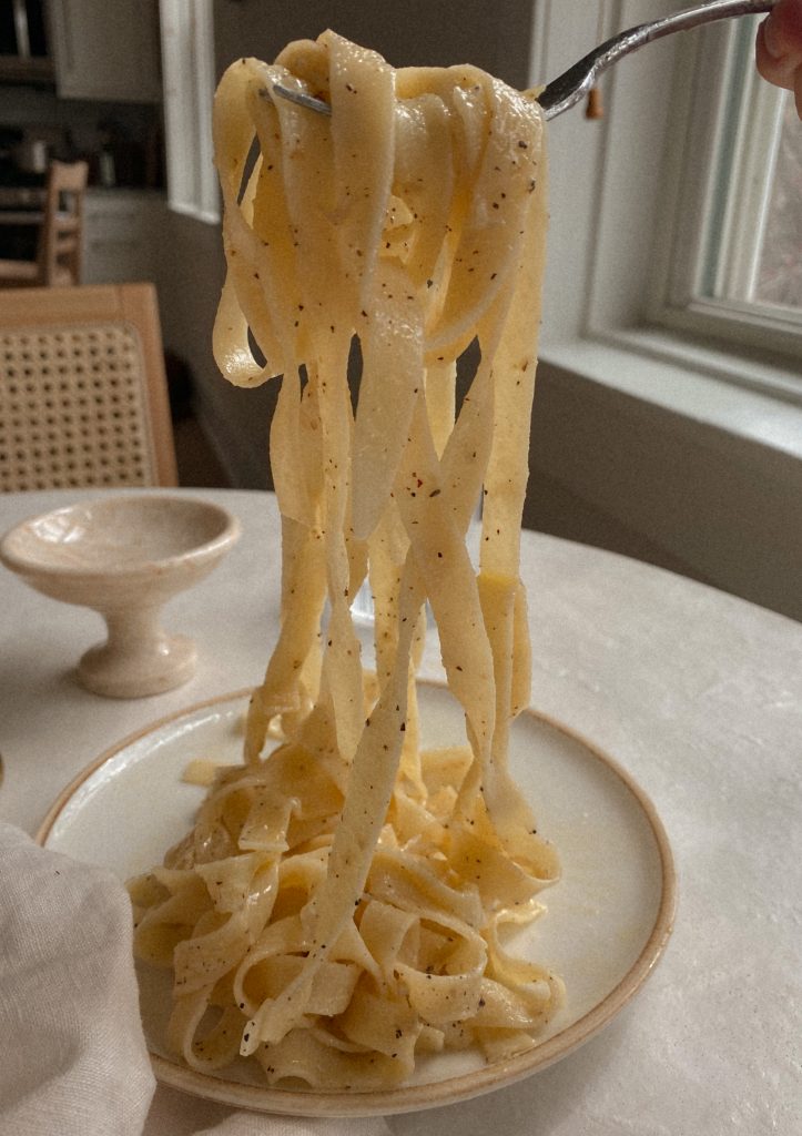 lemon parmesan fettuccine twirled on a fork in the air on a white plate