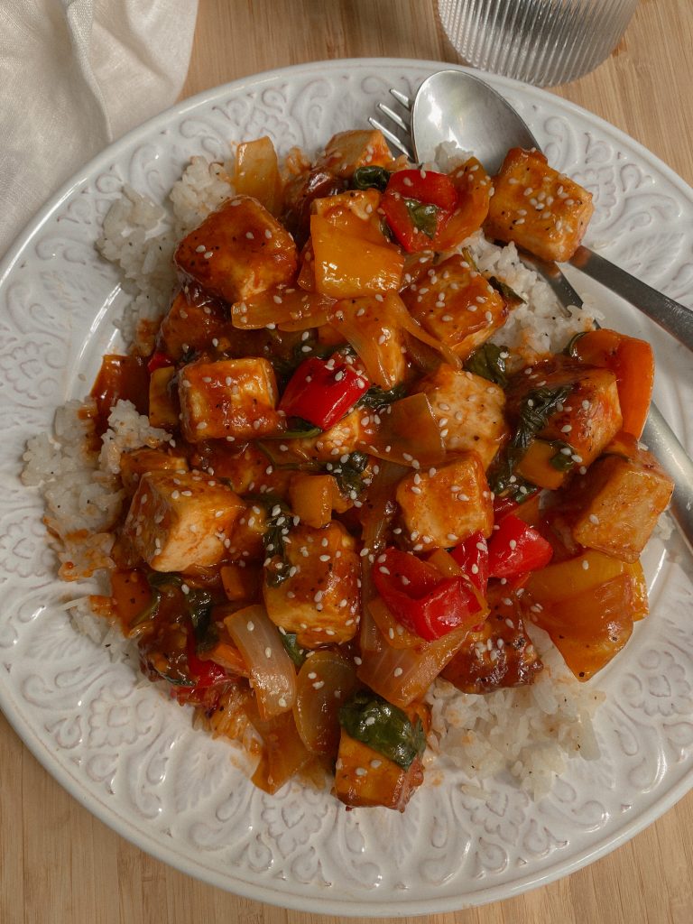 Vegan and Gluten Free Sweet Chili Tofu Recipe over white rice with mixed veggies served on a white glass plate. 