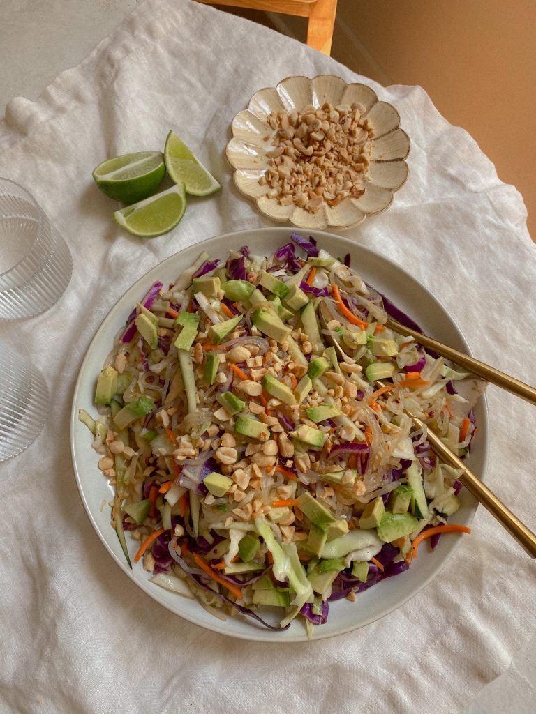 healthy gluten free and vegan asian noodle salad with avocado, cabbage, cucumber, green onions, and peanuts