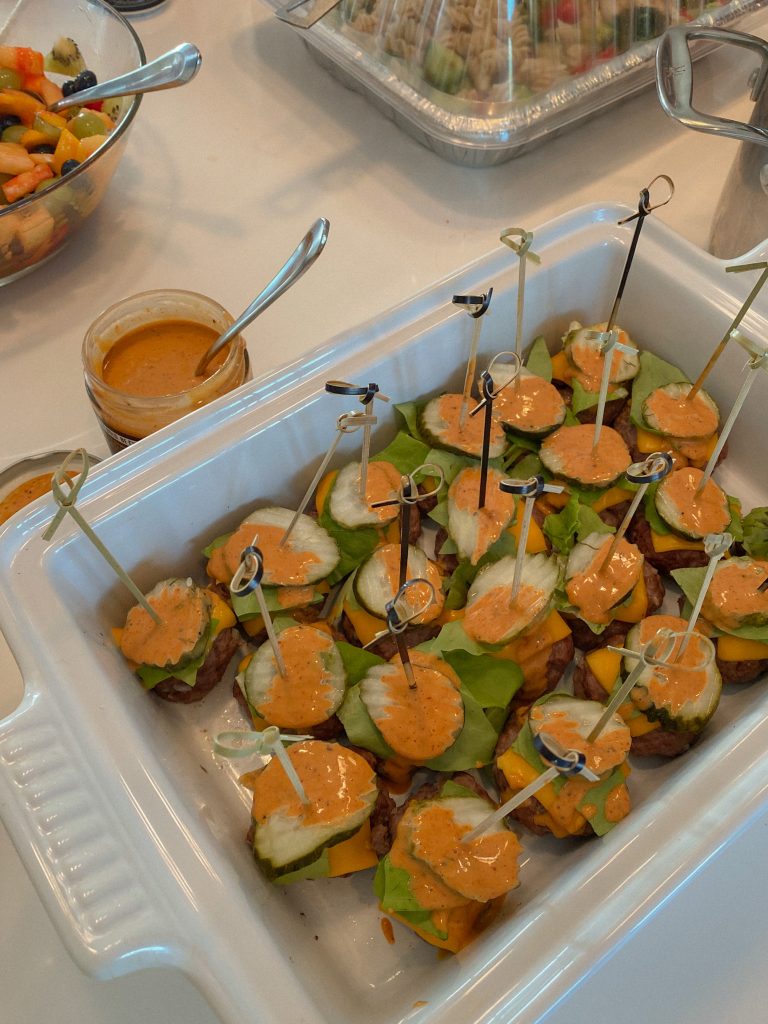 mini cheeseburger skewers with lettuce, pickles, and topped with burger sauce in a white serving dish 